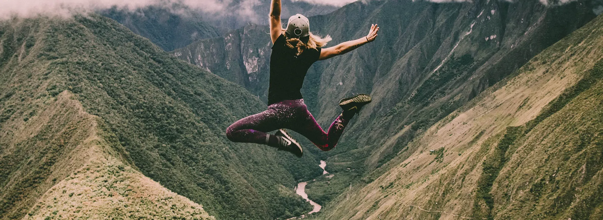 person jumping on a mountain